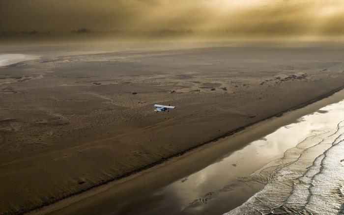 Airplane flying over a desert coast