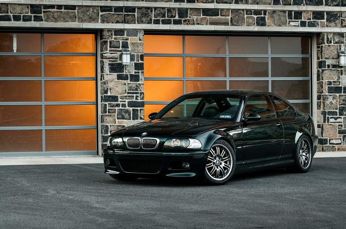 Black BMW E46 M3 parked in front of a garage