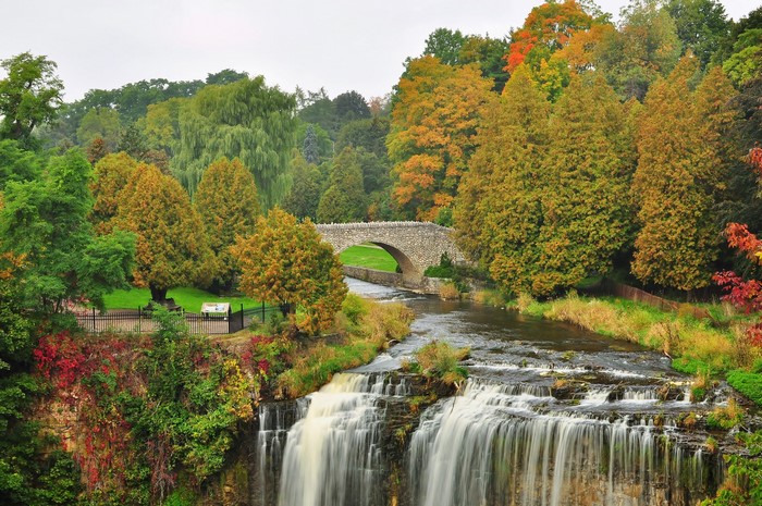 Waterfall and stone bridge in autumn park