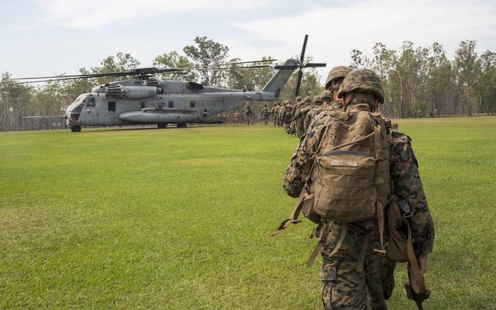 Marines boarding a helicopter on a grassy field