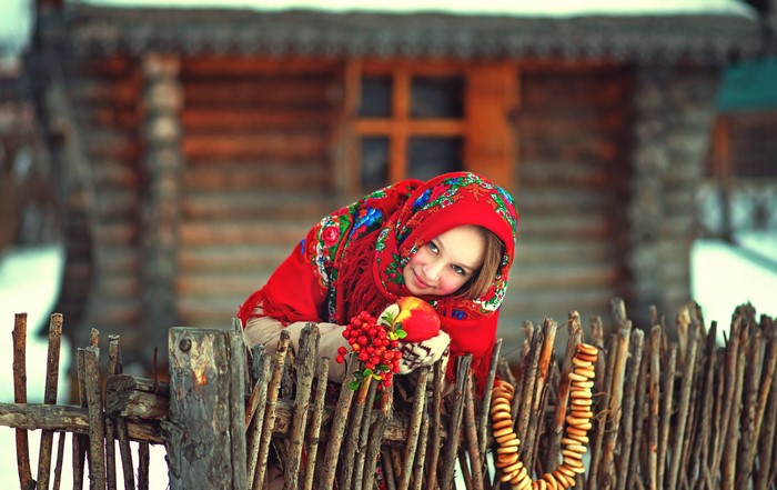 Girl in traditional Russian attire by a wooden fence