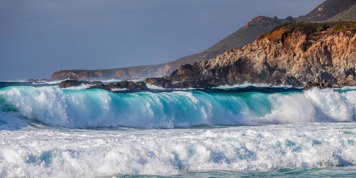 Turquoise waves crash against rocky coastline