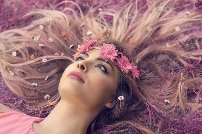 Blonde girl with flower crown lying in grass