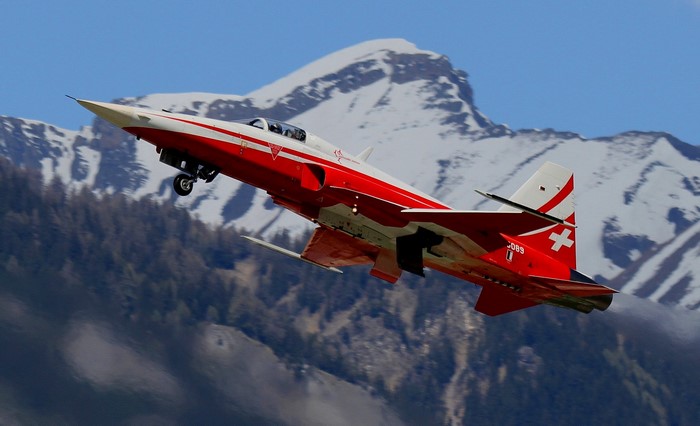Swiss F-5 Tiger II fighter jet flying over mountains