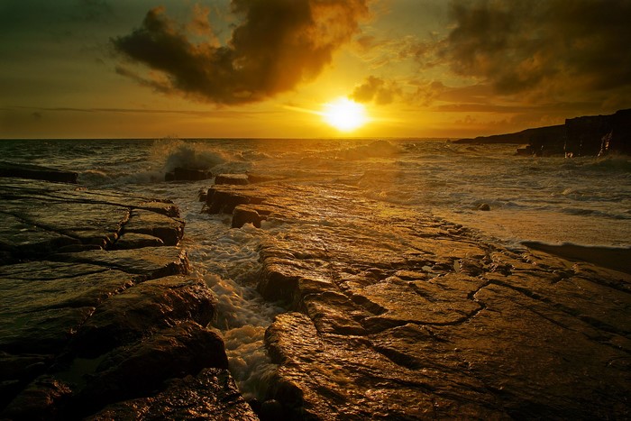 Sunset over the rocky coast with waves crashing