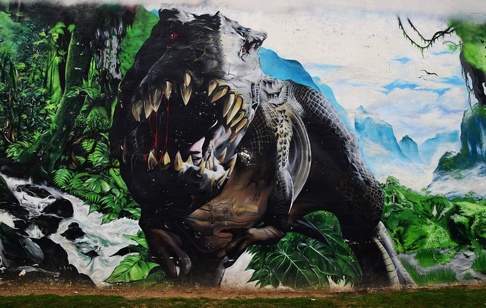 Graffiti painting of a dinosaur in a jungle landscape