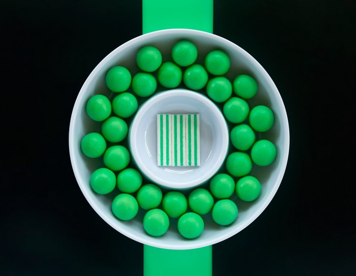 Green candies in a white bowl with striped candy