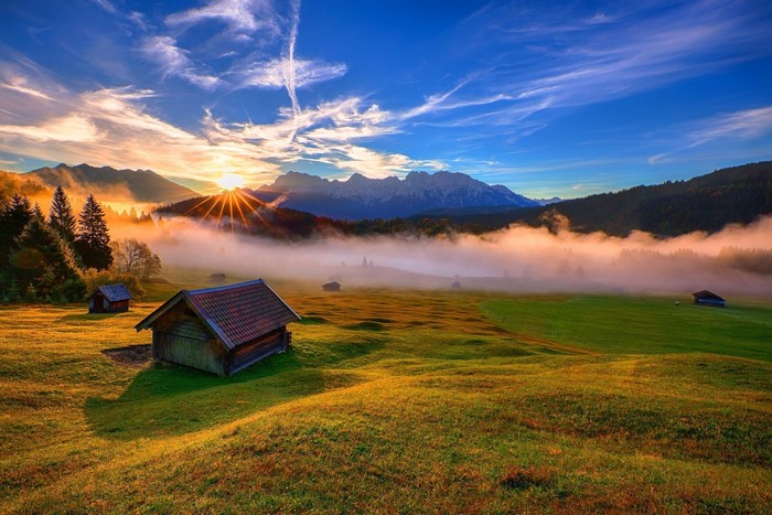 Sunrise over Bavarian Alps with fog and cabins