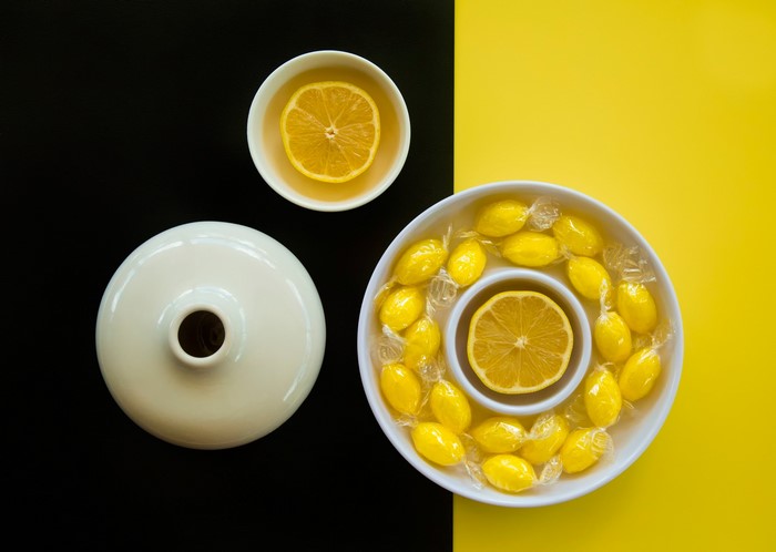 Lemons and candies arranged on a black and yellow background