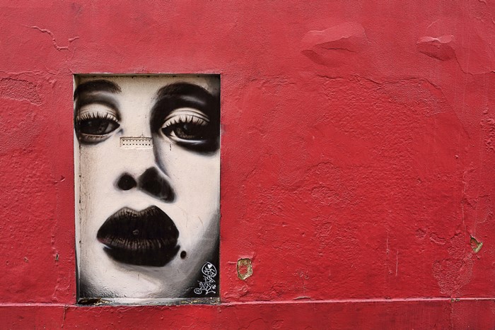 Graffiti of a woman's face on a red wall