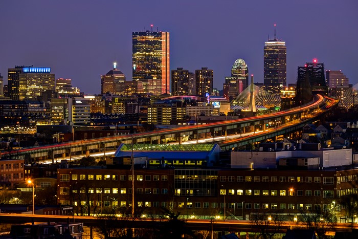 Boston skyline at night with illuminated buildings and highway