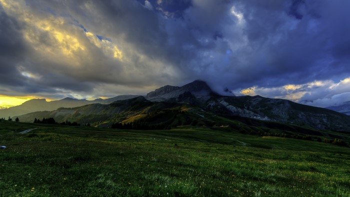 Mountains and clouds over a grassy field in France