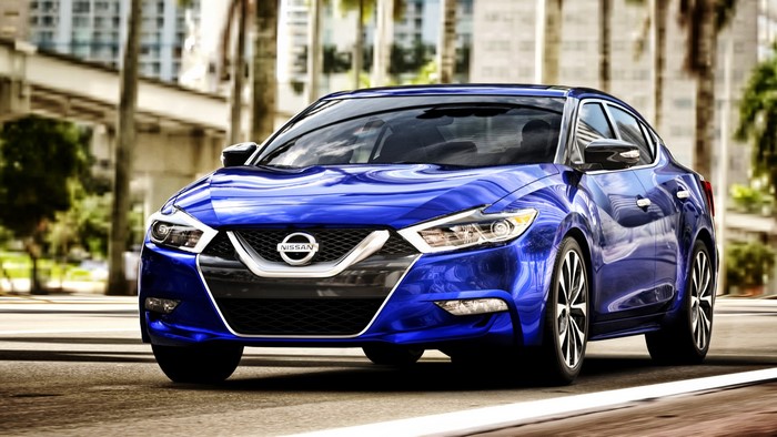 Blue Nissan Maxima Sedan Driving on City Street