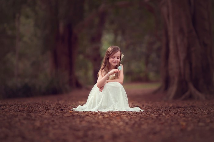 Girl in a white dress with a bird in a forest