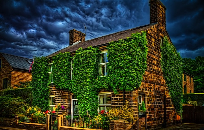 Stone house covered in ivy under stormy skies in Uppermil, England