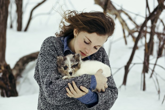 Girl holding a puppy in the snow
