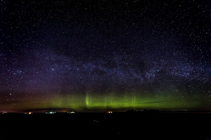 Aurora Borealis and Milky Way over a dark landscape