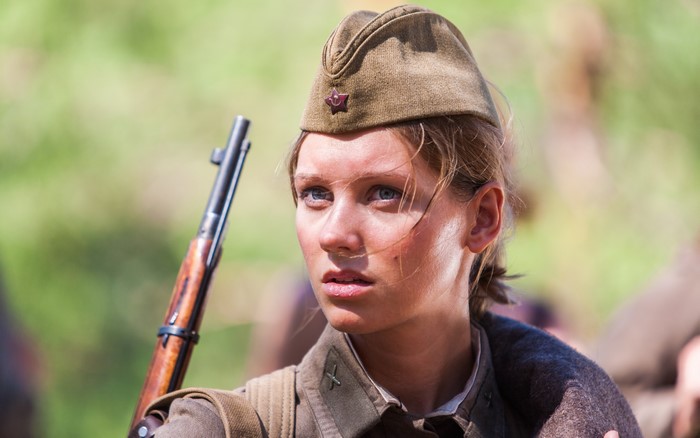 Young woman in military uniform with rifle