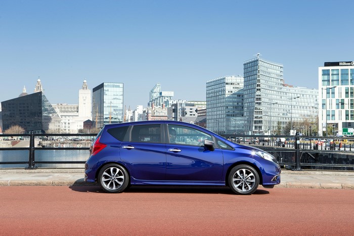 Blue 2015 Nissan Note parked by a waterfront with city skyline