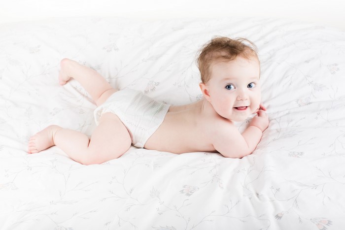 Baby in a diaper lying on a patterned bed