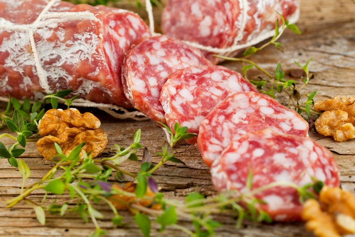 Slices of salami with walnuts and herbs