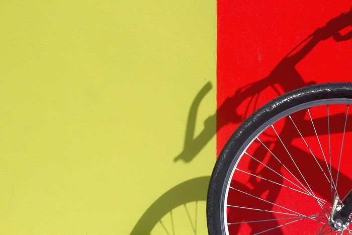 Bicycle wheel and shadow on a red and yellow wall