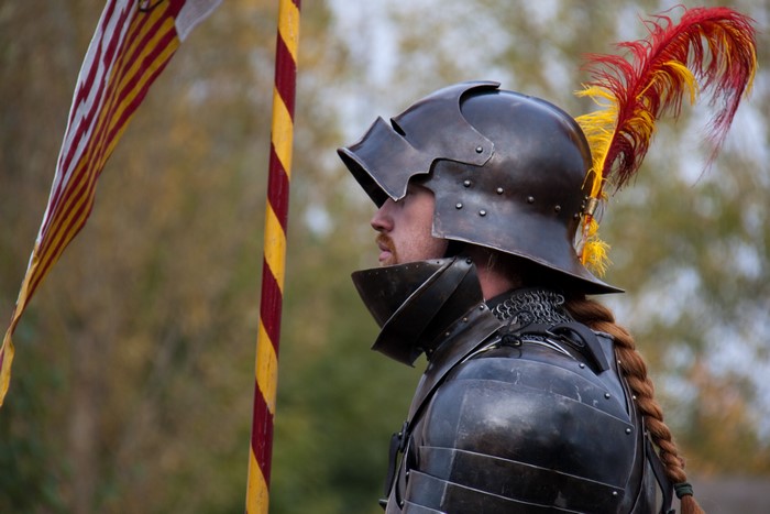 Knight in armor with a feathered helmet and banner