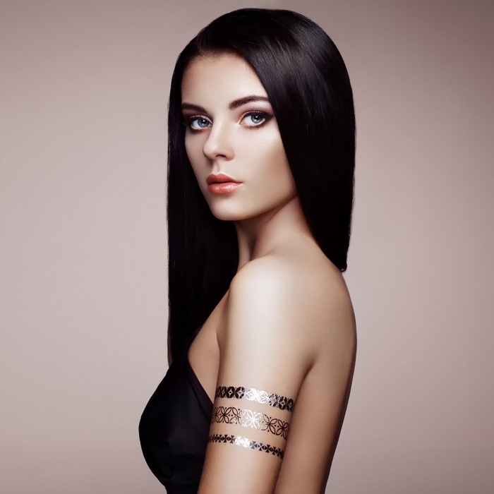 Elegant woman with dark hair and metallic arm tattoos