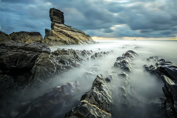 Rocky coastline with misty sea and dramatic clouds