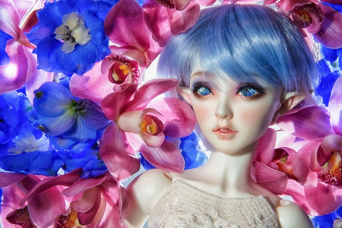 Elf doll with blue hair surrounded by pink and blue flowers