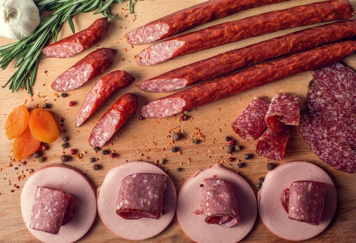 Sausages, Spices, Garlic, and Dried Apricots on a Wooden Board