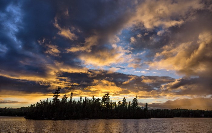 Lake and forest at sunset with dramatic clouds