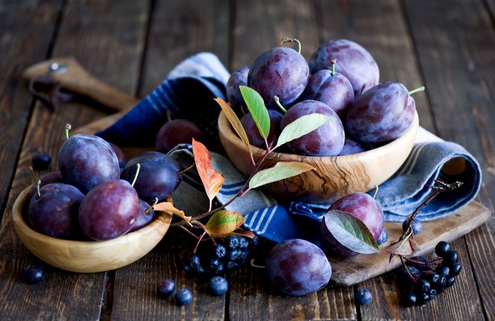 Plums and aronia berries on wooden table