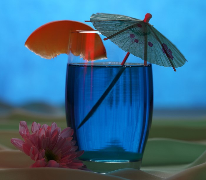 Blue drink in a highball glass with umbrella and orange slice