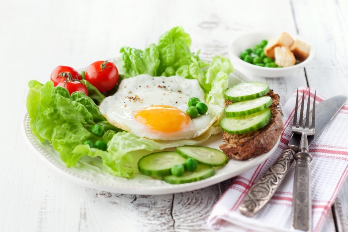 Fried egg with salad and toast on a plate