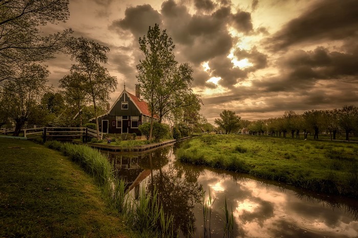 A Dutch house by a canal under a cloudy sky
