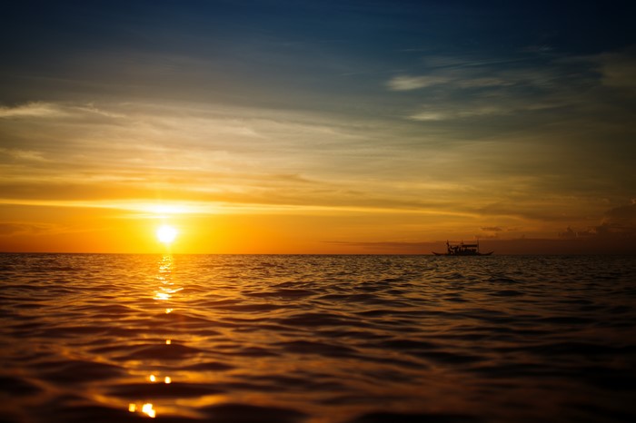 Sunset over the sea with a boat on the horizon