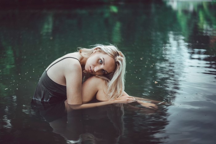 Blonde girl sitting in dark water