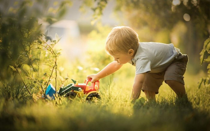 Boy playing with toy tractor in grass