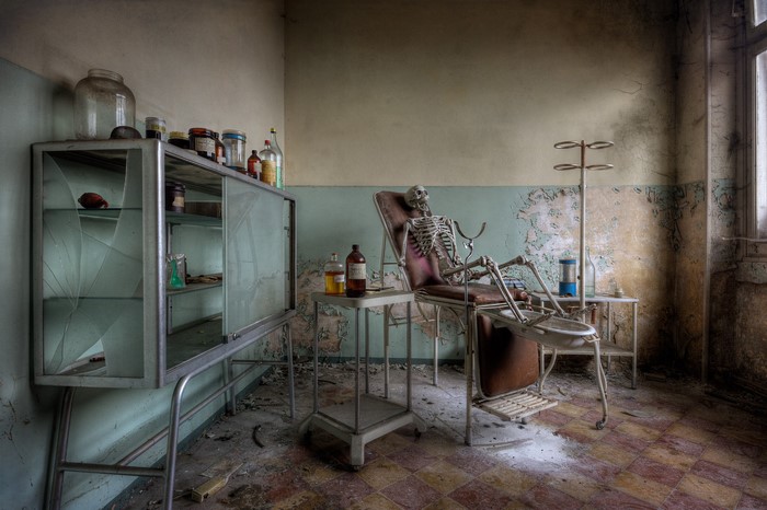 Skeleton in abandoned medical room with cabinet