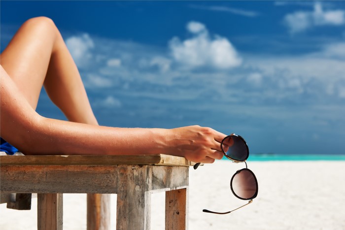 Woman holding sunglasses on a beach