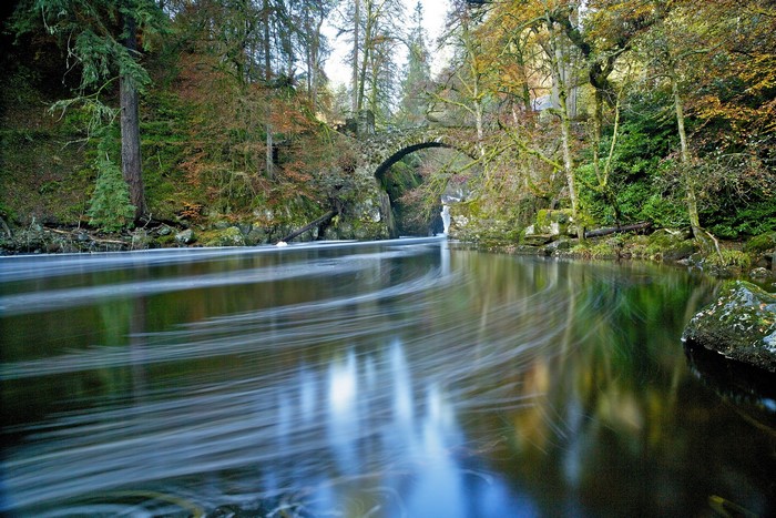 Stone bridge over a river in an autumn forest