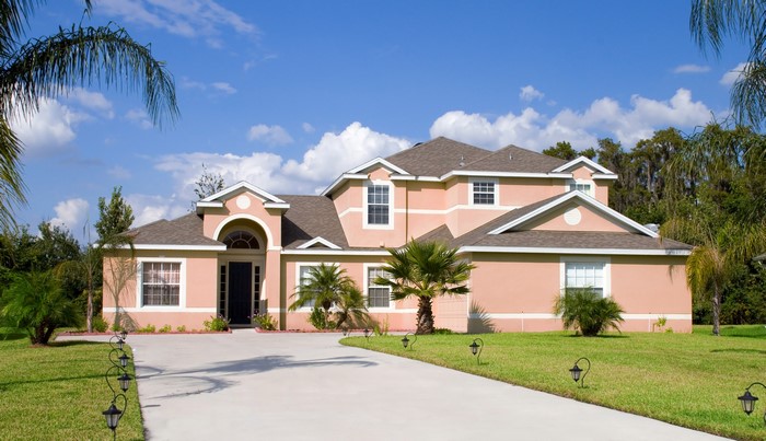Peach-colored mansion with palm trees and lawn