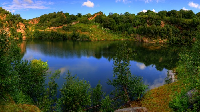 Summer lake surrounded by trees and rocky hills