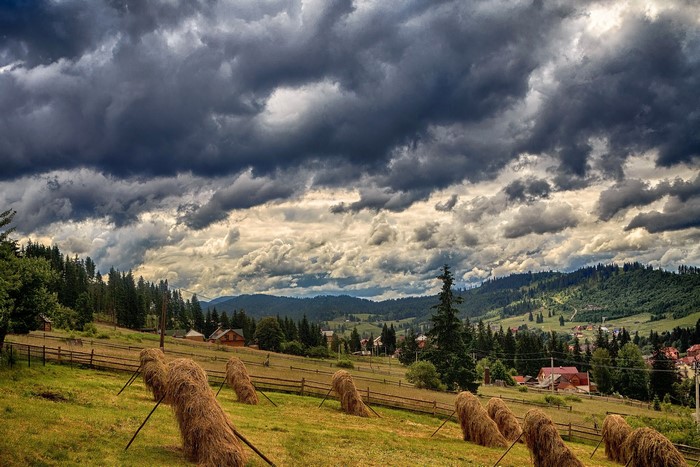 Haystacks in the Carpathian Mountains under stormy clouds
