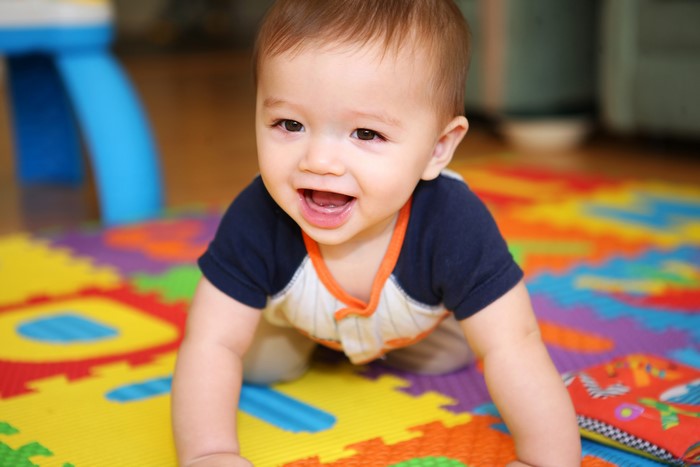 Baby boy crawling on a colorful mat