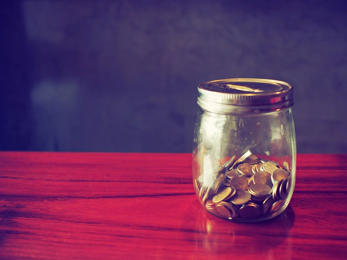 Coins in a glass jar on a red table