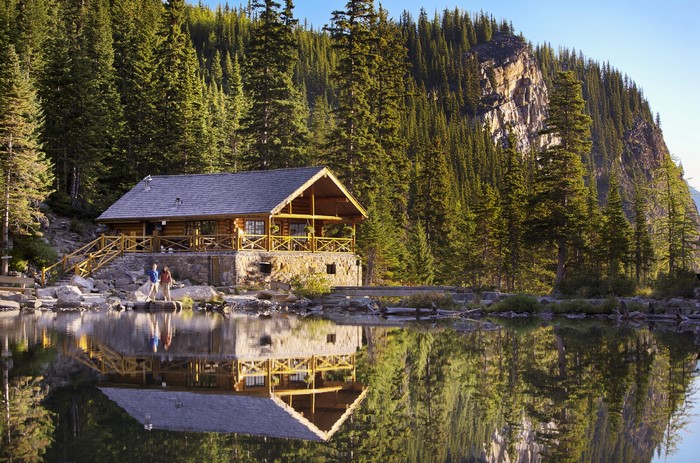 Log cabin by a lake with mountains and forest in Banff