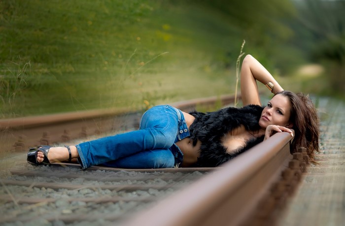 Woman in Jeans Lying on Railroad Tracks