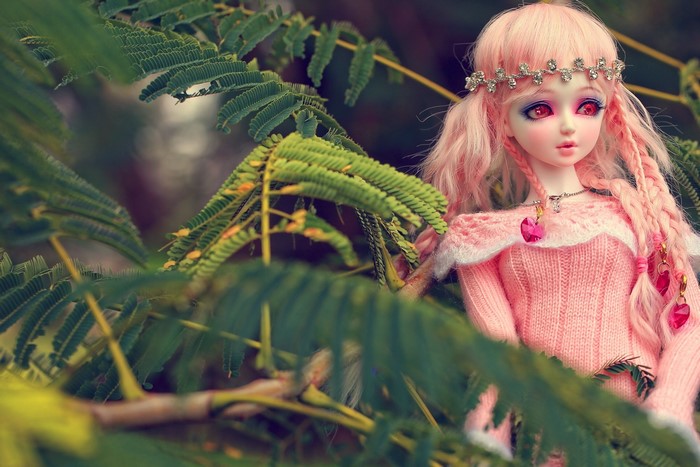 Doll with pink hair and pink dress in foliage